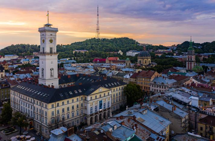 Arieal view of city of Lviv with city hall and a hill in the background during a sunset.